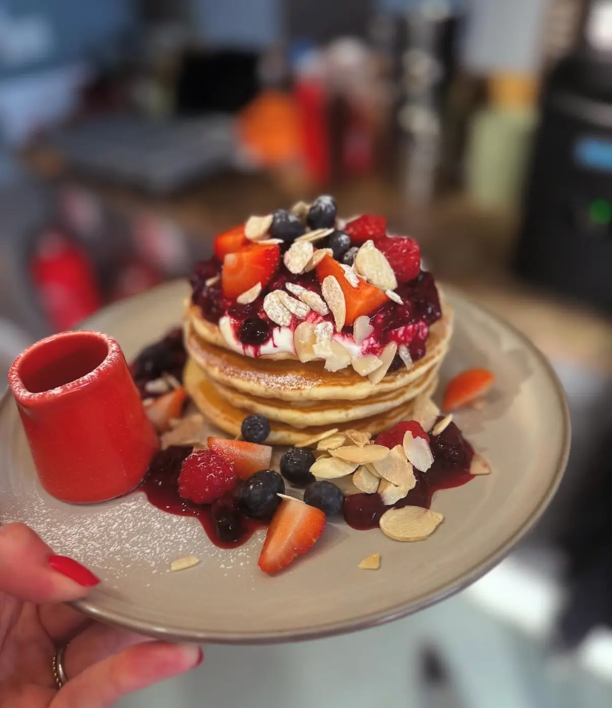 A pancake stack with berries, yogurt and flaked almonds