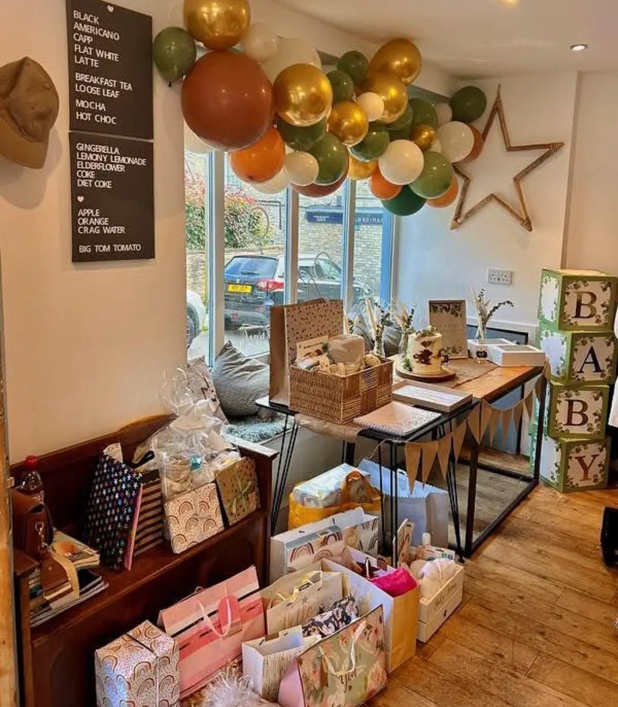 Balloons, gifts and a cake set up for a baby shower inside The Green