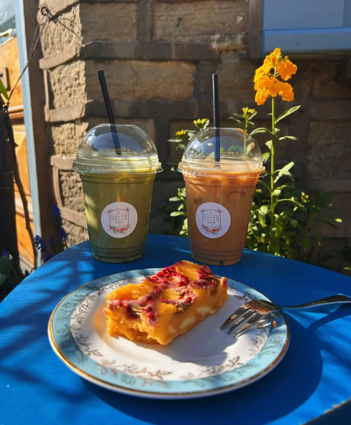 An iced matcha and iced coffee to go beside a homemade bake